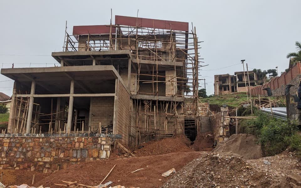 Multi-level building under construction with scaffolding on a Kigali hillside